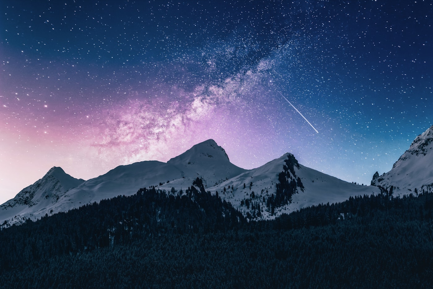 Distant snow-capped mountain peaks under a moody deep blue sky